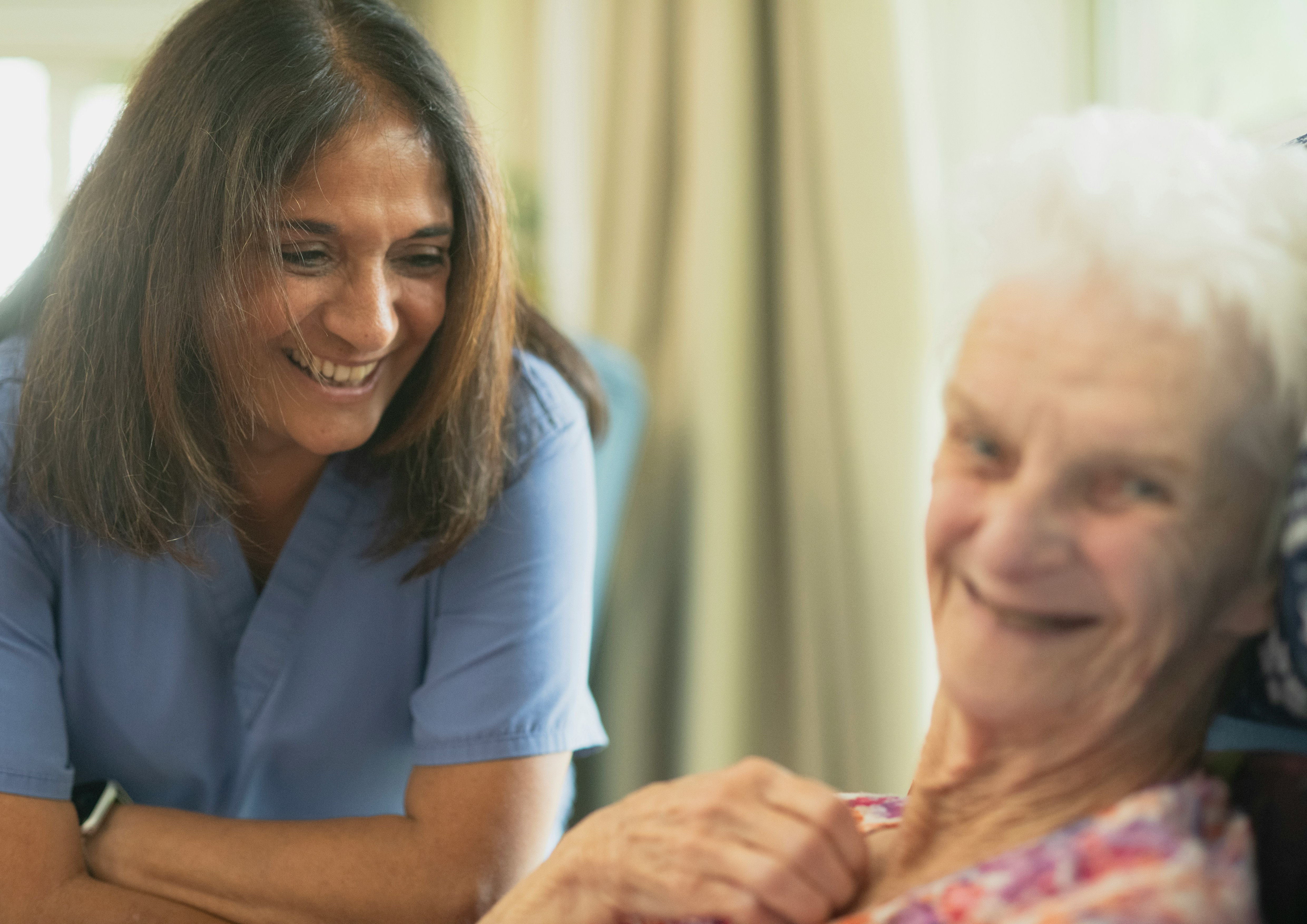 A caregiver and an older woman sharing a laugh